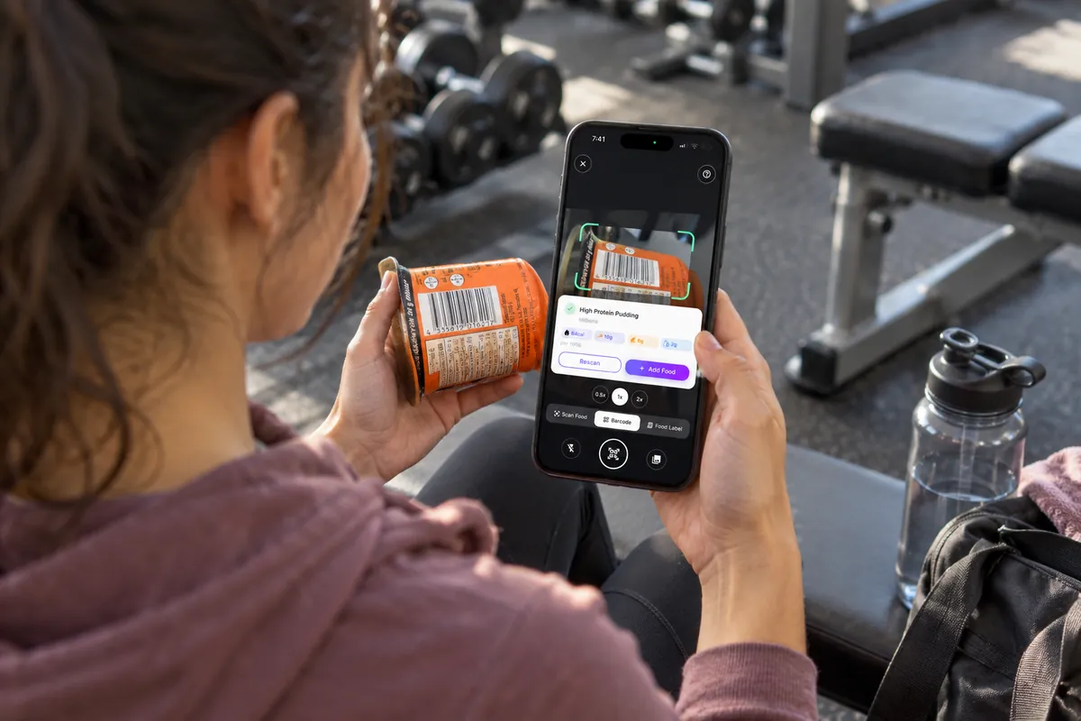 Eine Frau scannt im Fitnessstudio mit Smart Calorie Tracker den Barcode eines Proteinpuddings.